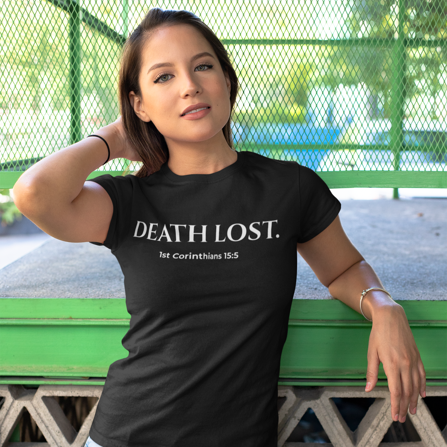 Woman wearing a black t-shirt with 'DEATH LOST' text, standing outdoors.