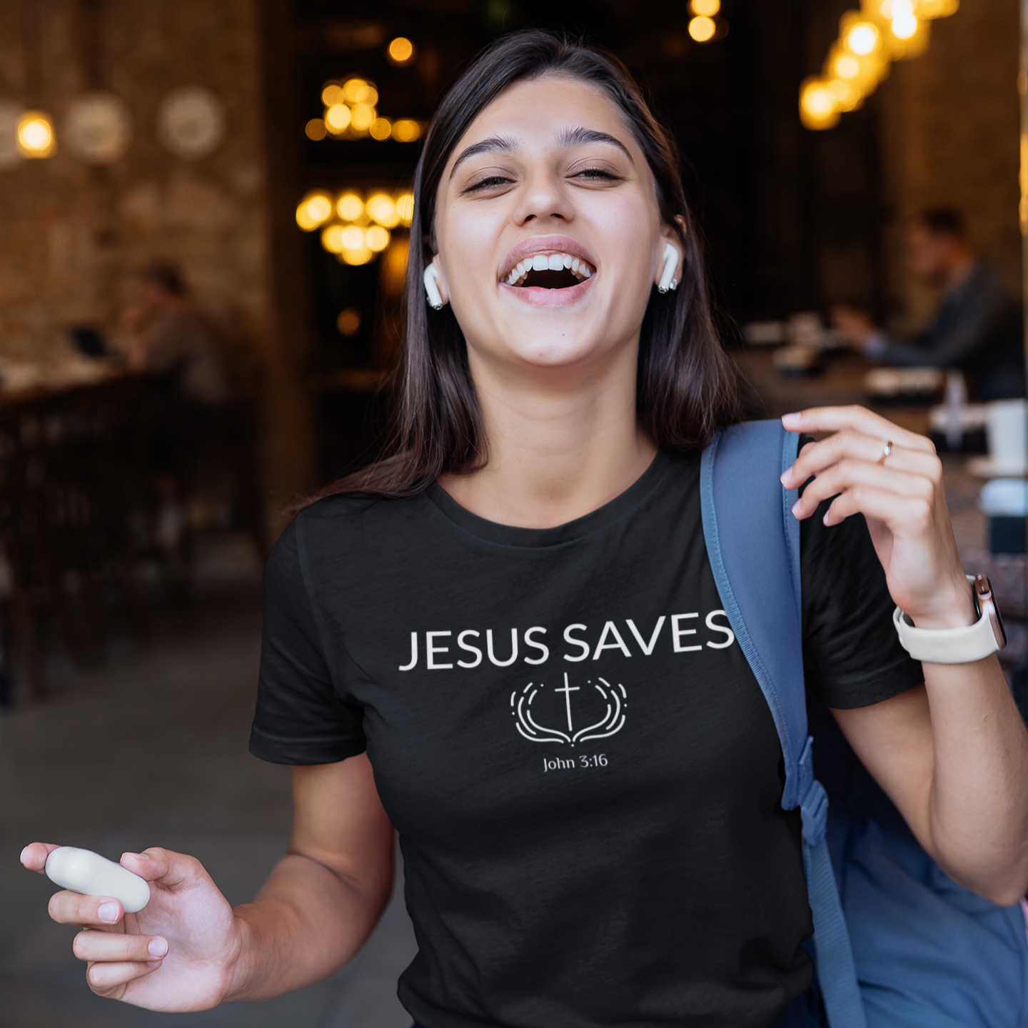 Woman wearing a black t-shirt with 'Jesus Saves' text in a casual setting.