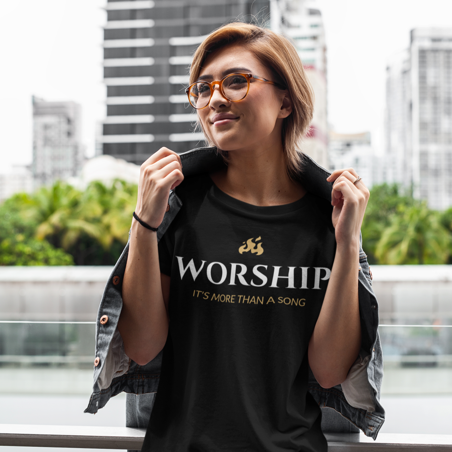 Person wearing a black t-shirt with 'Worship It's More Than A Song' text, standing outdoors with buildings in the background.