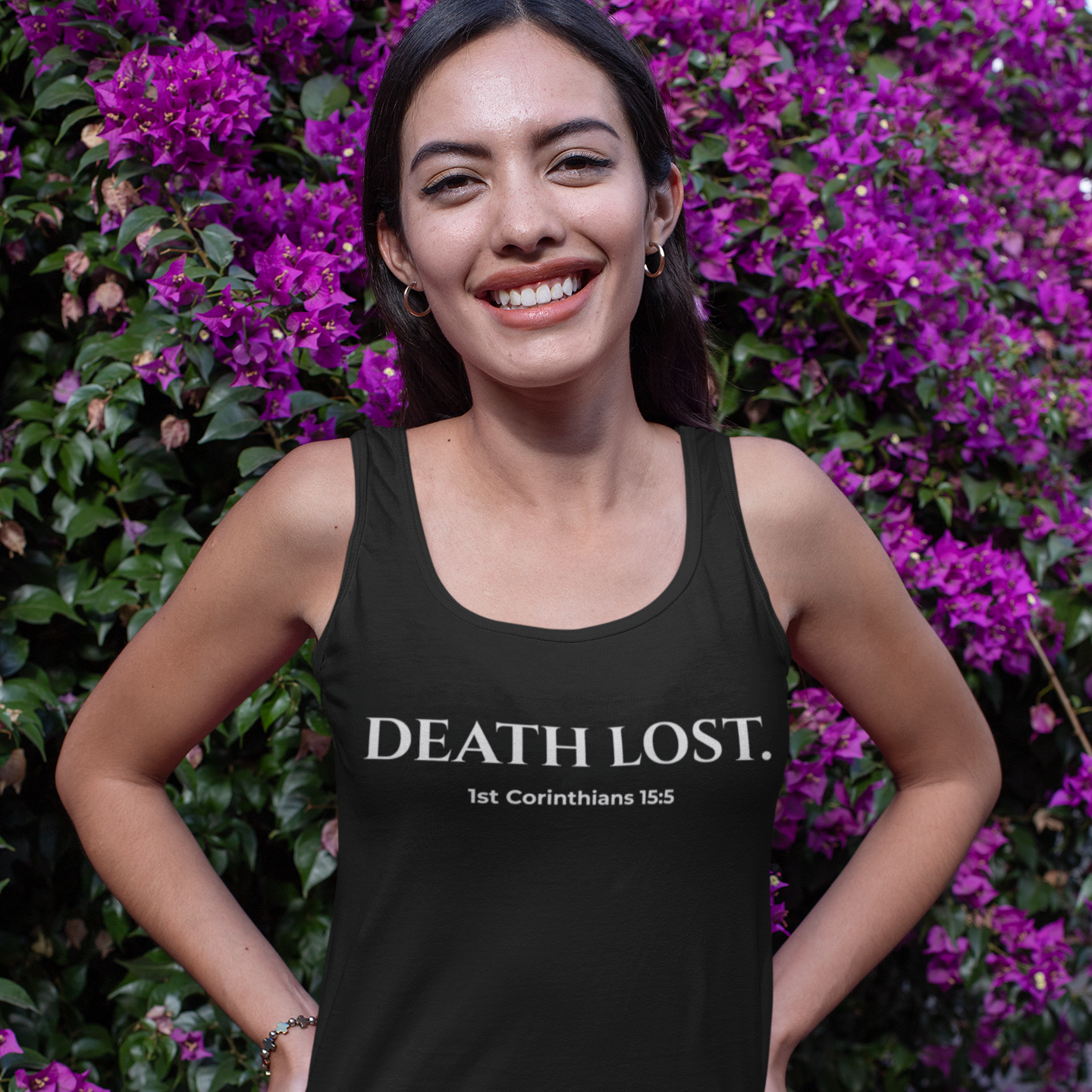 Woman wearing a black tank top with 'DEATH LOST' text, standing in front of purple flowers.