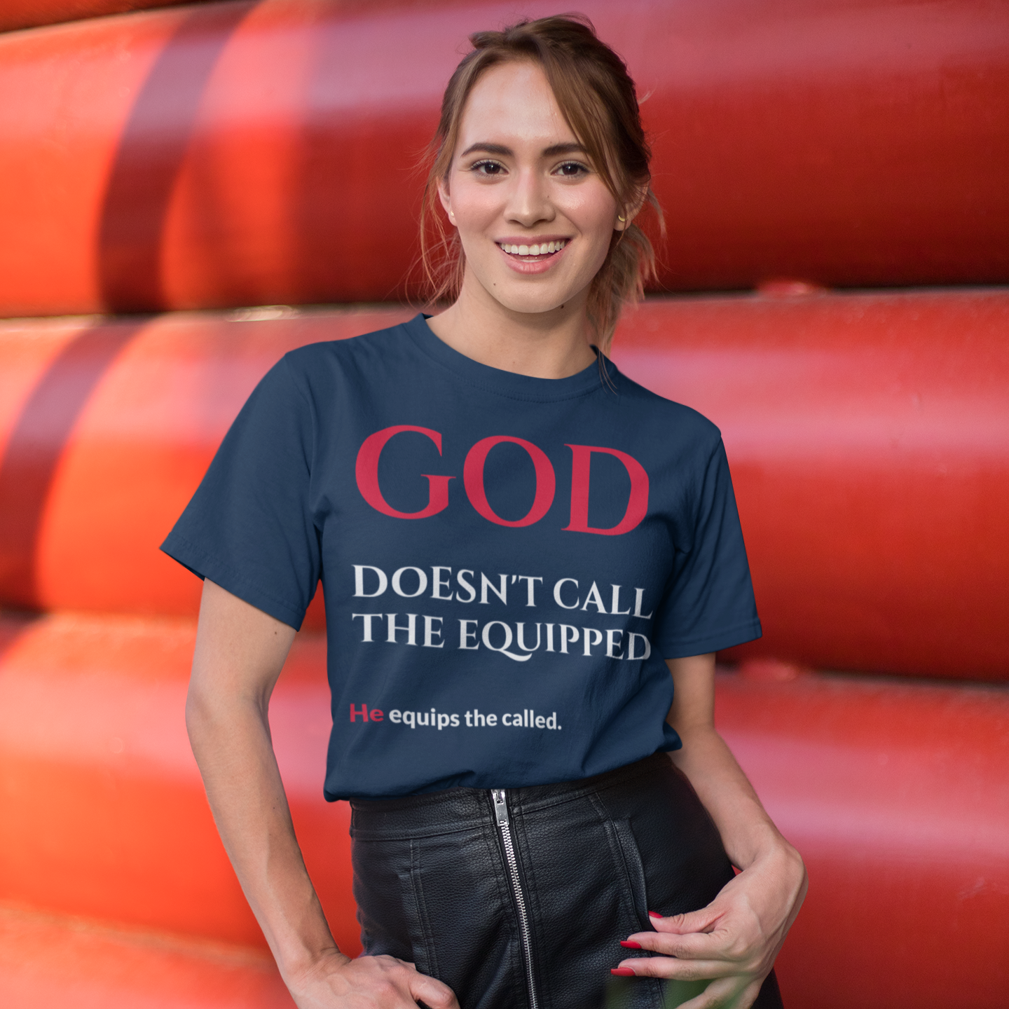 Woman wearing a blue t-shirt with a motivational quote, standing in front of red pipes.