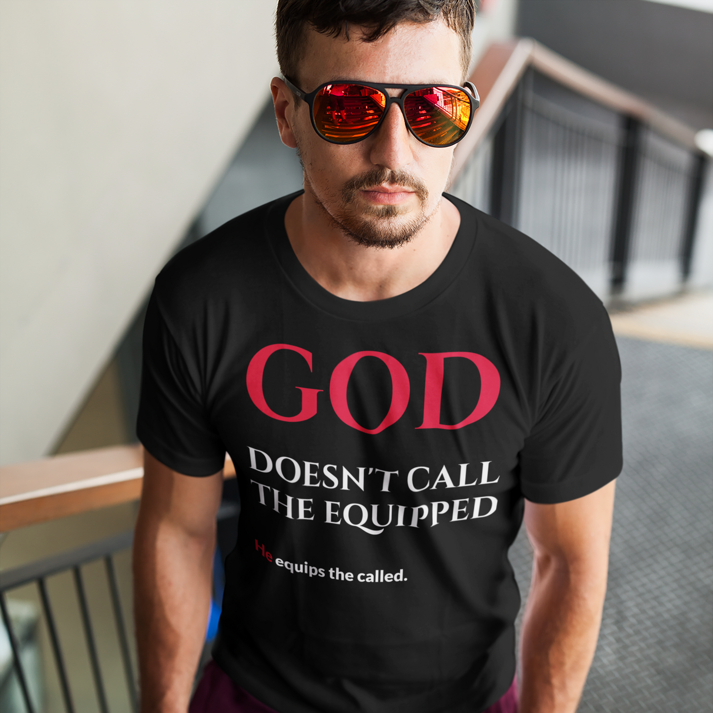 Man wearing a black t-shirt with red and white text, standing on a staircase.