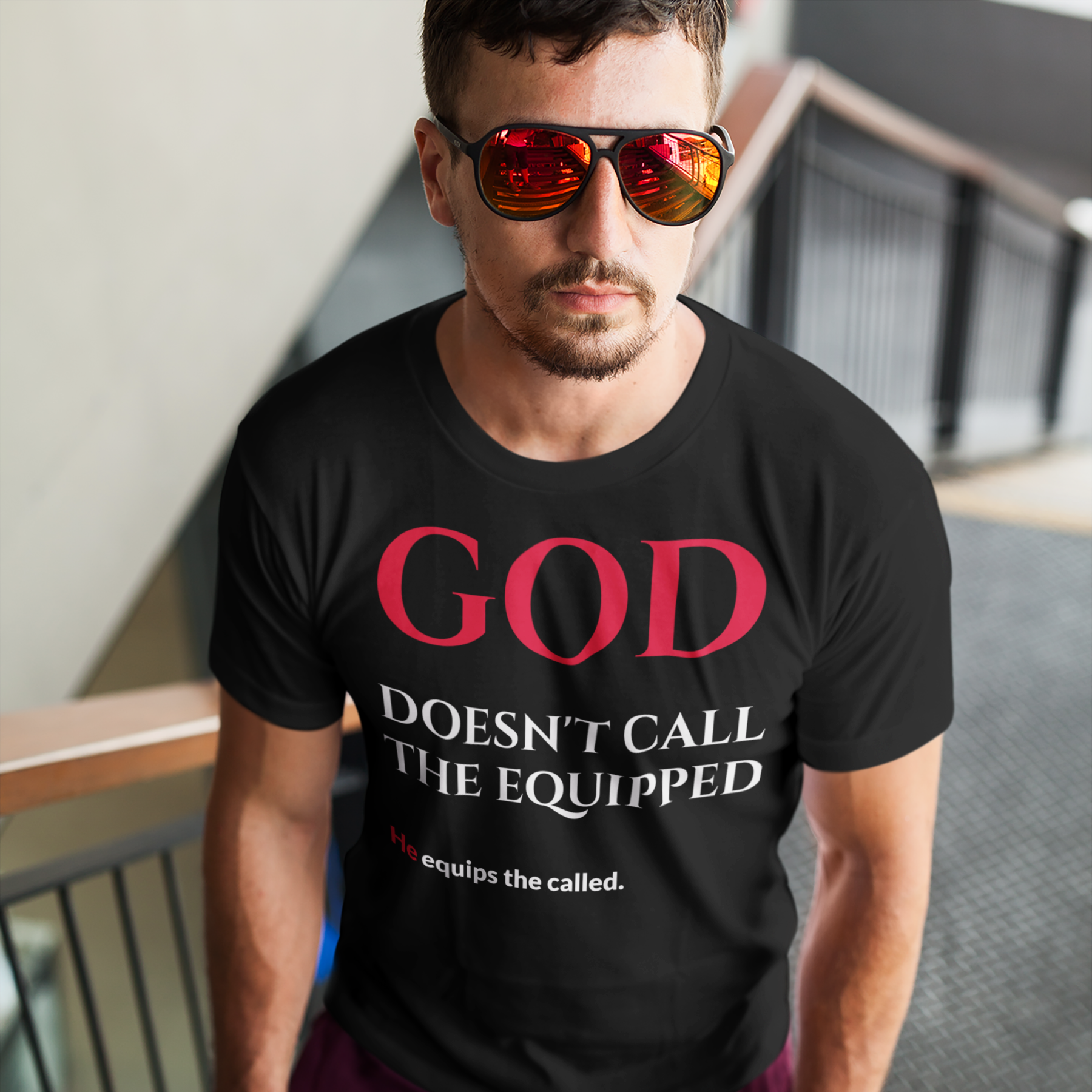 Man wearing a Black t-shirt with red and white text that says 'god doesn't call the equipped he equips the called'.