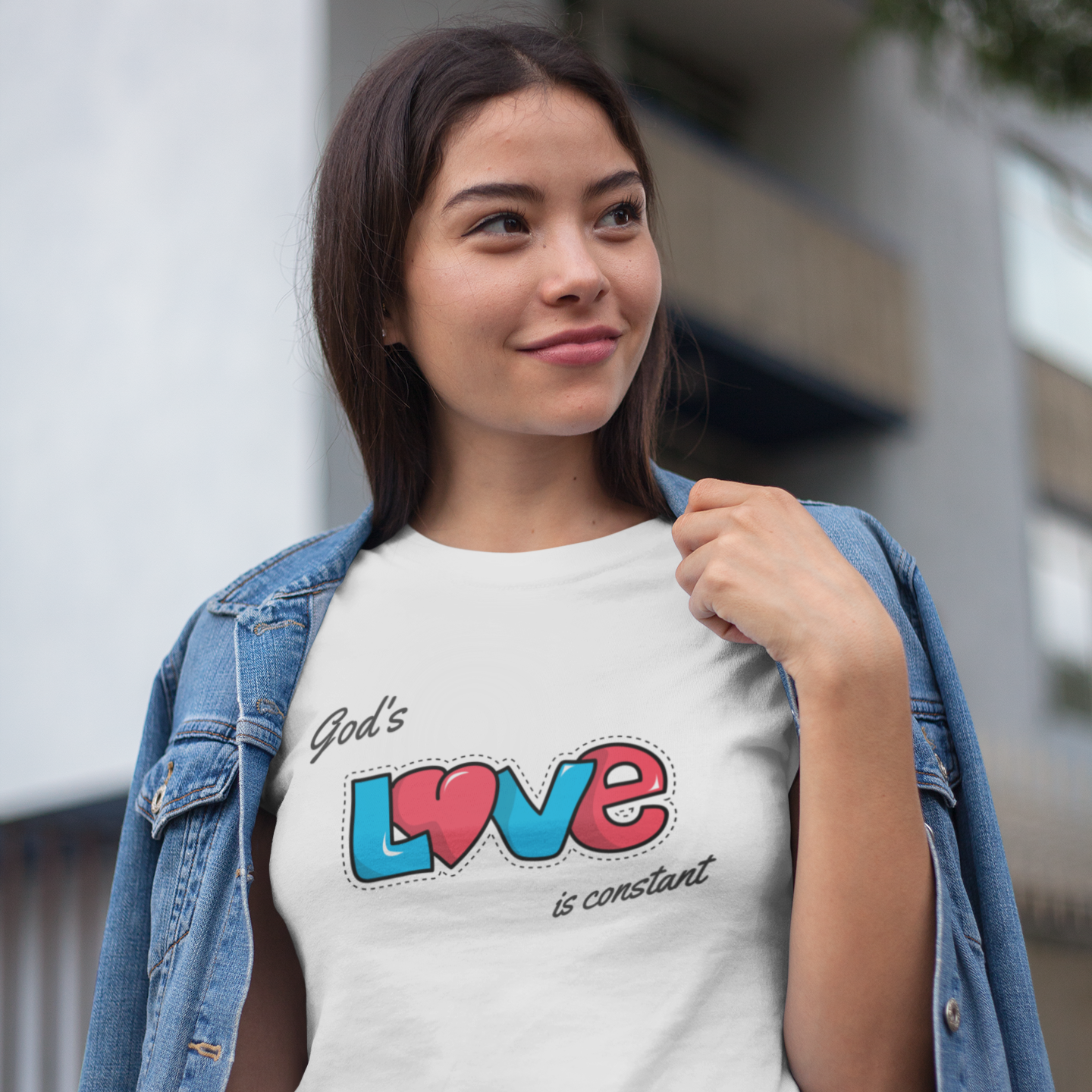 Woman wearing a t-shirt with 'God's love is constant' text and colorful design.