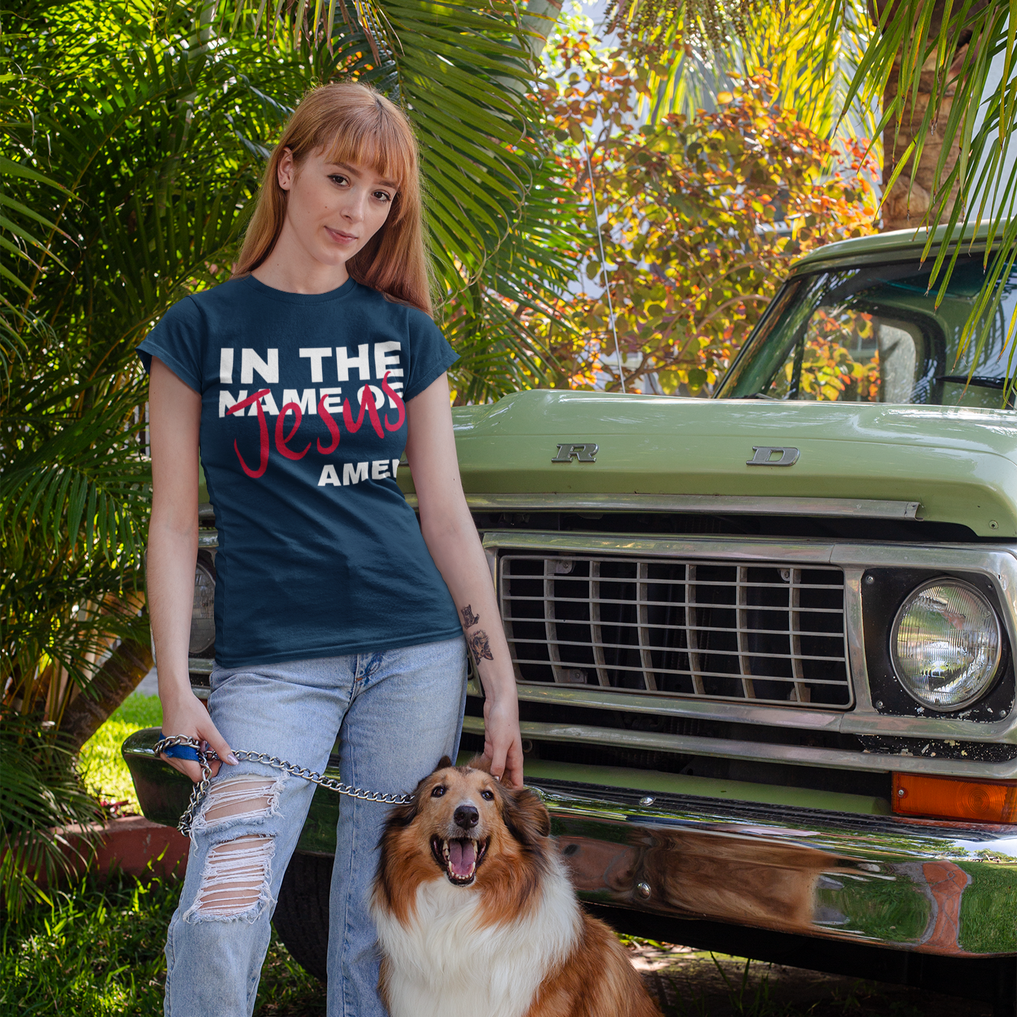 Woman wearing a t-shirt with text standing next to a dog in front of a vintage truck.