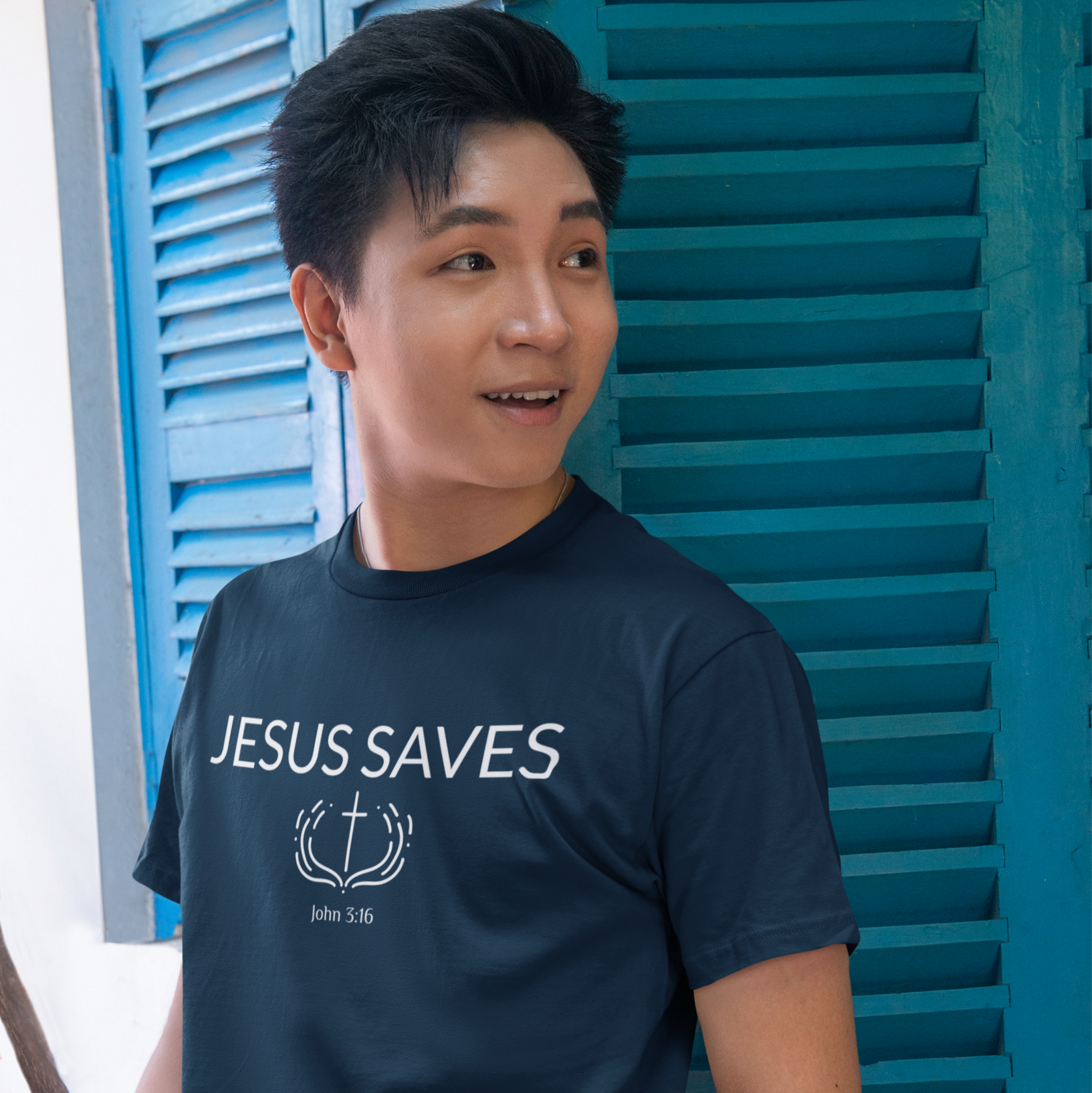 Person wearing a navy blue t-shirt with 'Jesus Saves' text, standing in front of blue shutters.